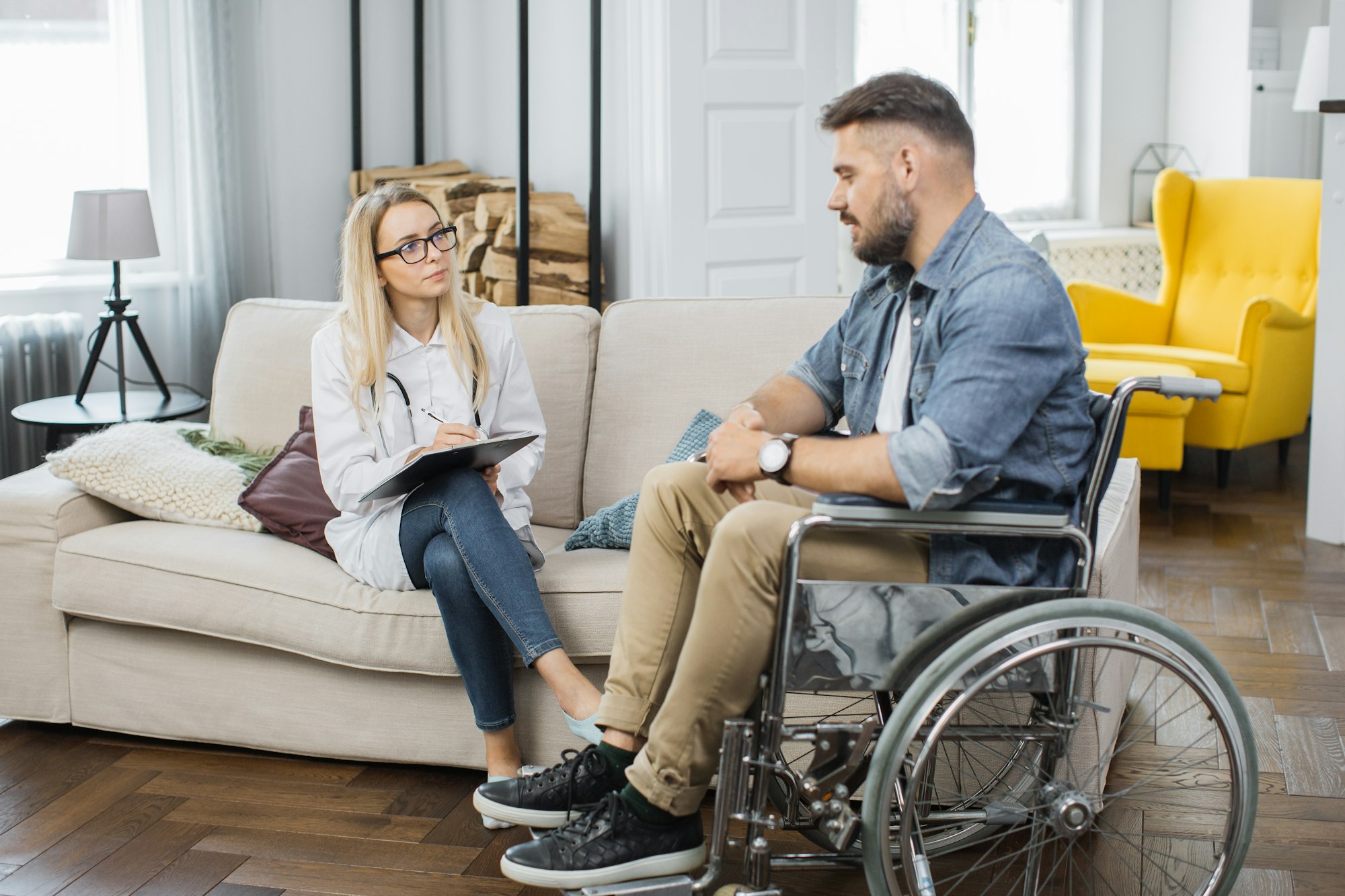 Healthcare worker examining man in wheelchair at home